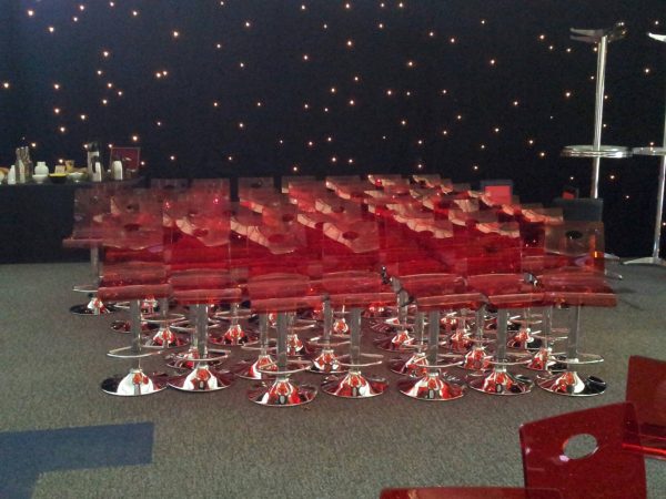 Red gas lift plastic swivel bar stool with a chrome base and foot rest - BE Event Hire